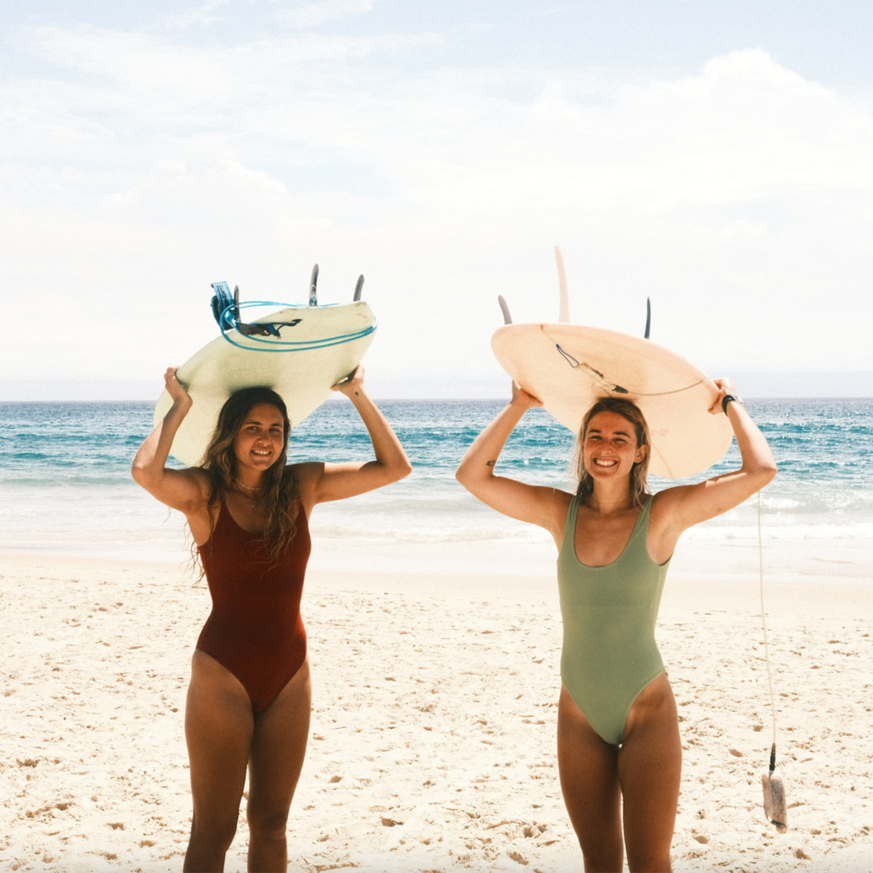 Happy Dkoko customers at the beach wearing their favorite Dkoko surf bikinis with their boards after a surf session.