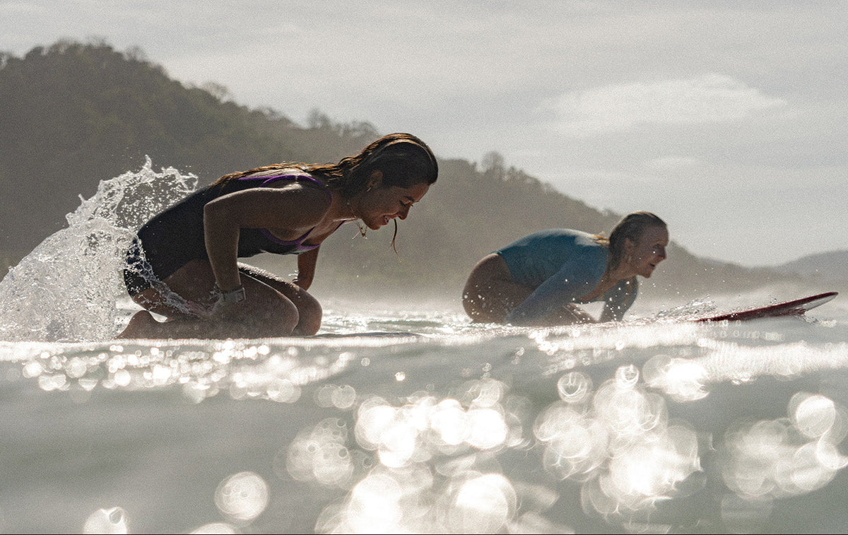 Lia Diaz and Delilah paddling out in longboards surfing in Costa Rica wearing Dkoko one piece swimwear